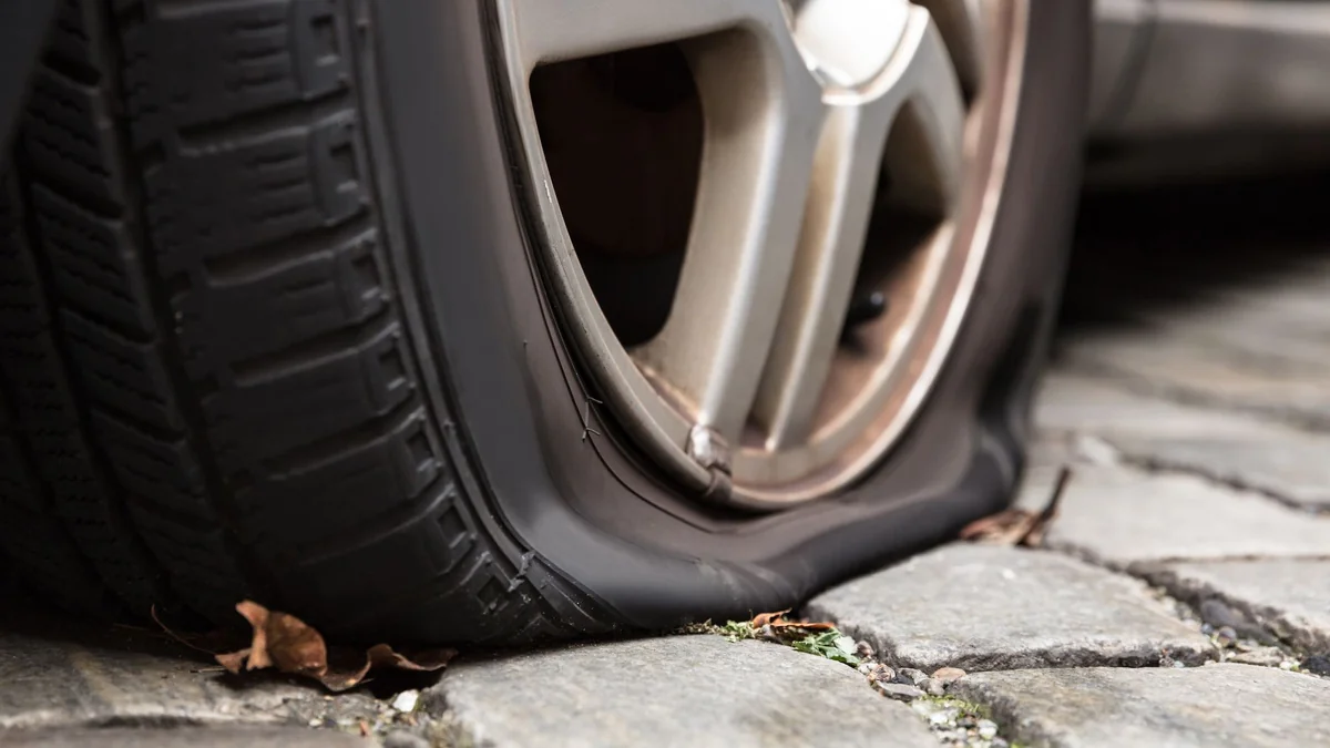 Спущенная шина при низком давлении Спущенная автомобильная шина с сильной деформацией боковины из-за низкого давления