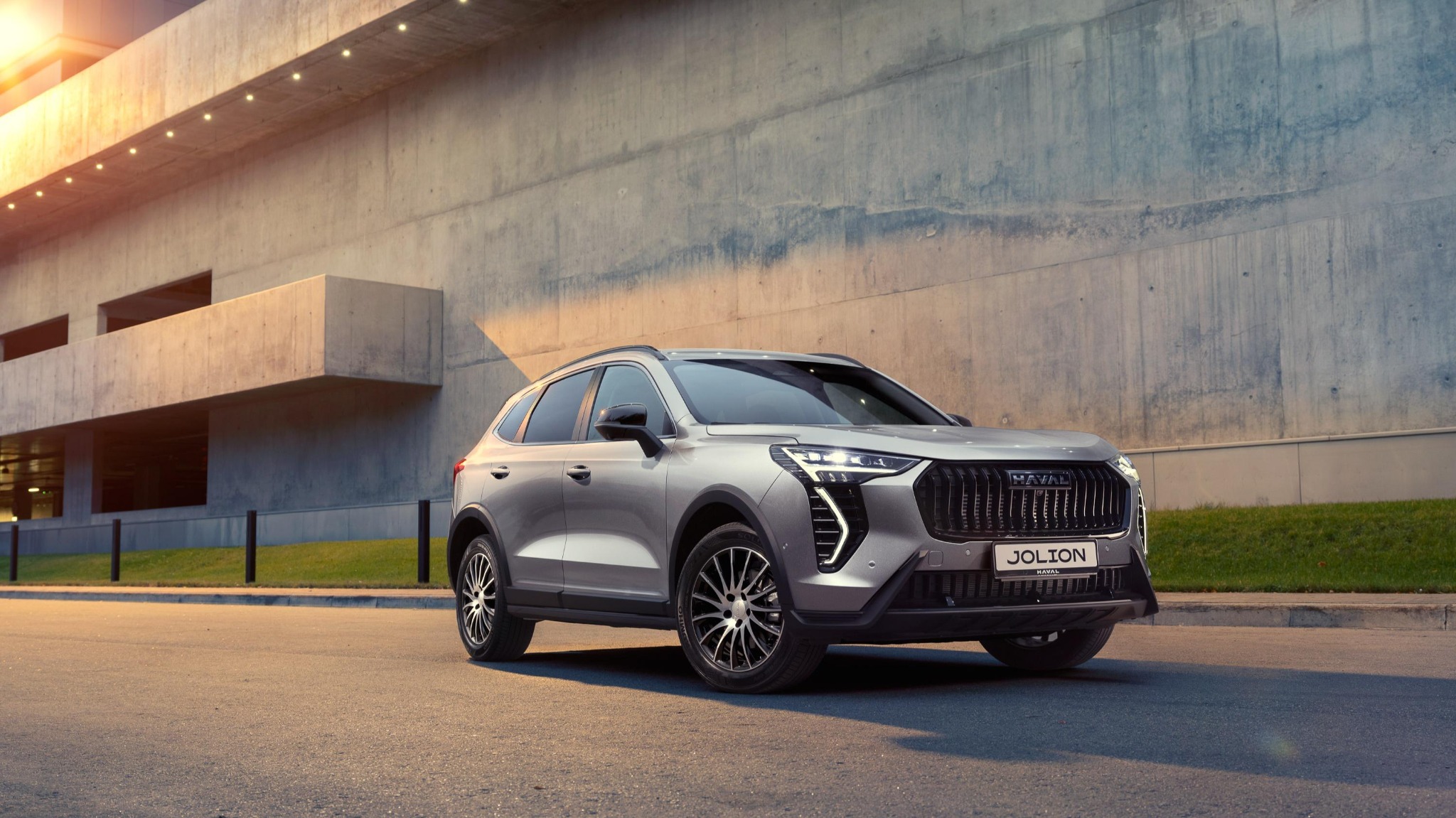 Haval Jolion у здания Haval Jolion у современного здания — городской китайский кроссовер